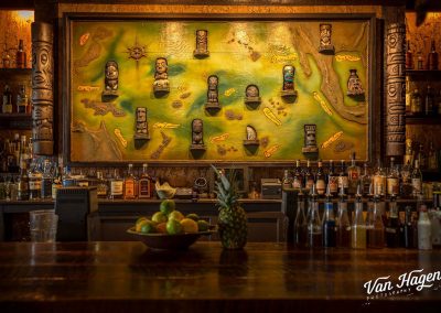 Image of the back bar from Latitude 29 (New Orleans) shows a large map populated with tiki mugs of various regions